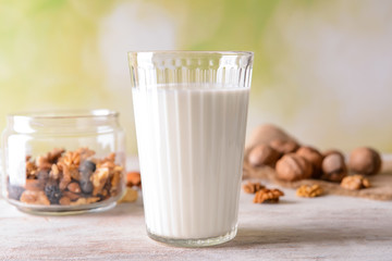 Glass of tasty milk and nuts on light table