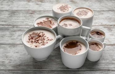 Many cups with tasty aromatic coffee on wooden table