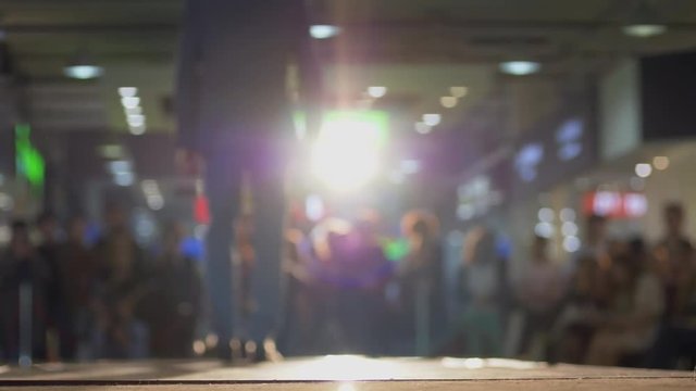 male model in solid suit and shoes walk the podium during a fashion show in backlight on background blurred audience