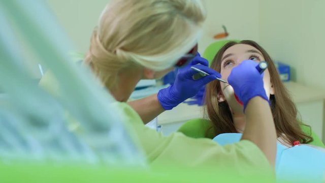 Dentist working with dental curing light in oral cavity. Process of polymerization of dental composite in dentist office. Tooth filling in dental clinic. High technology stomatology