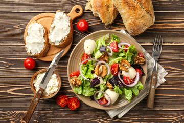 Delicious fresh salad with walnuts on wooden table
