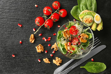 Delicious fresh salad with walnuts in glass bowl on dark table