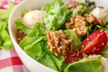 Delicious fresh salad with walnuts in bowl, closeup