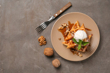Tasty waffles with ice cream and nuts on plate