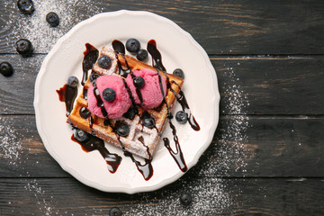 Tasty waffles with berries and ice cream on plate