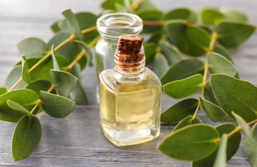 Bottles with essential oil and eucalyptus branches on wooden table © Pixel-Shot