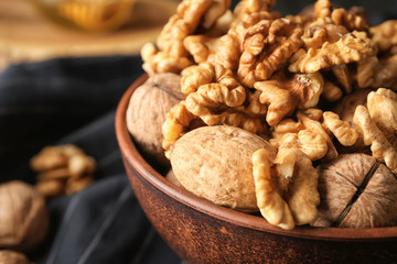 Bowl with tasty walnuts on table, closeup