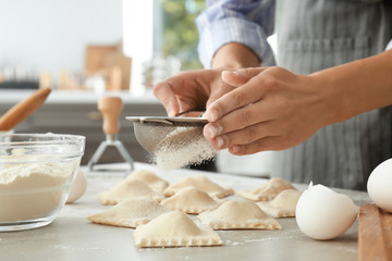 Woman making tasty ravioli on table