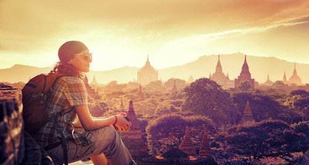 woman traveler sitting and looking sunset and enjoying the view stupas on Bagan - obrazy, fototapety, plakaty