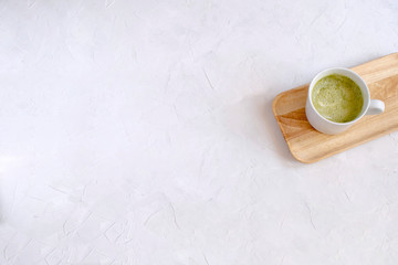 Matcha latte in white cup on wooden tray