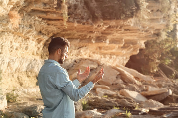 Young Muslim man praying outdoors