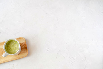 Matcha latte in white cup on wooden tray