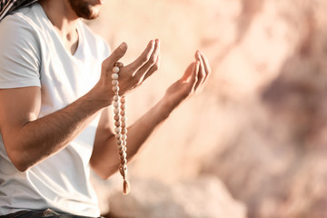 Young Muslim man praying outdoors