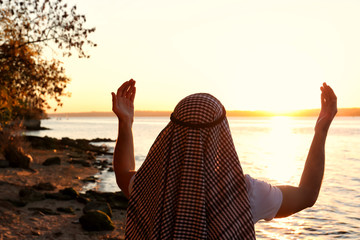 Young Muslim man praying near river