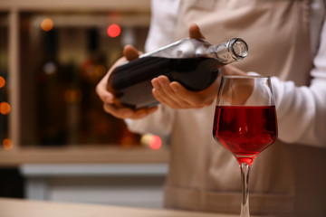 Female barman pouring wine from bottle into glass