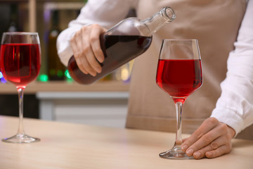 Female barman pouring wine from bottle into glass on counter