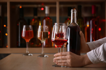 Female barman with bottle and glass of wine at counter