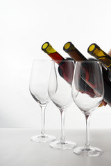 Pouring of different wine from bottles into glasses on white background