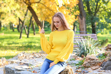 Beautiful young woman with autumn leaf in park