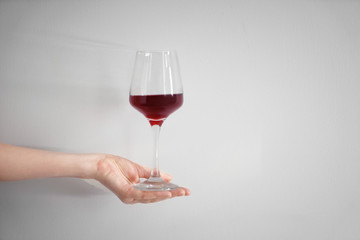 Female hand with glass of red wine on white background