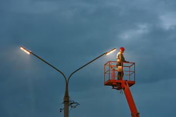 Municipal worker with helmet and safety protective equipment installs new diode lights. Worker in...