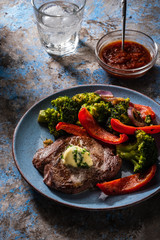 Grilled Beef steak with garlic butter and vegetables. Meat with grilled bell pepper, broccoli and onions.