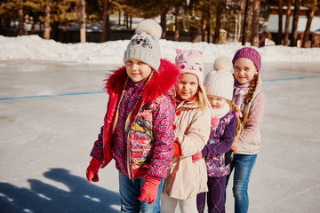 Four little happy girls are skating. They have fun with friends.