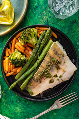 Pike perch fillet with asparagus, broccoli and carrots. Fried fish with stewed greens