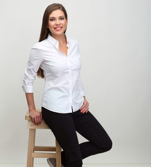 Smiling woman in white shirt sitting on barstool.