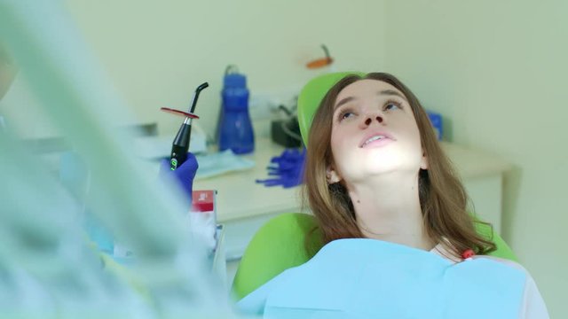 Tooth filling in dental clinic. Finishing treatment process with dental curing light. Dentist working in patient oral cavity. Process of polymerization of dental composite. High technology stomatology