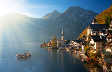Fototapeta na wymiar Scenic view of famous Hallstatt mountain village in the Alps with traditional passenger ship at autumn morning