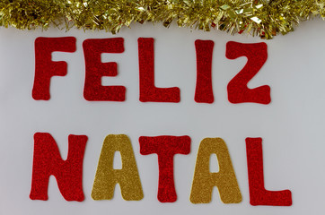 Christmas card. Merry Christmas greeting message written in Portuguese "Feliz Natal". White background . Top view