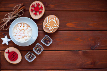 Cup of chocolate with marshmallow, gingerbread cookies, gifts and beautiful Christmas decorations on the wooden background. Flat lay, top view, space for a text.