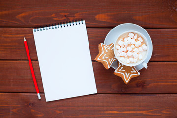 Open notebook with blank pages, gifts, cup of chocolate with marshmallow and sweets. Flat lay, top view. Christmas planning and New Year concept, holiday decorations 2019 Goals. 