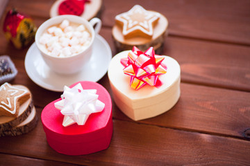Obraz na płótnie Canvas Cup of chocolate with marshmallow, gingerbread cookies, gifts and beautiful Christmas decorations on the wooden background. Flat lay, top view, space for a text.