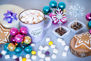 Hot coffee with marshmallows and gingerbread cookies on the light gray background. Beautiful Christmas decorations with gifts and sweets. Space for a text. Close up.