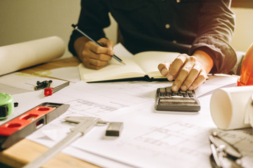 Concept architects,engineer holding pen pointing equipment architects On the desk with a blueprint in the office, Vintage, Sunset light.Selective Focus
