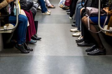 Feet of people sitting opposite each other in a subway car. The concept of spending life time waiting