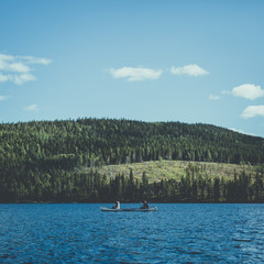 Two people kayaking across a lake in the woods in Swedish lapland