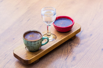 Turkish coffee, a glass of water and a chocolate snack are served on a designer tray on a wooden table. Stylishly decorated service in the cafe and restaurant.