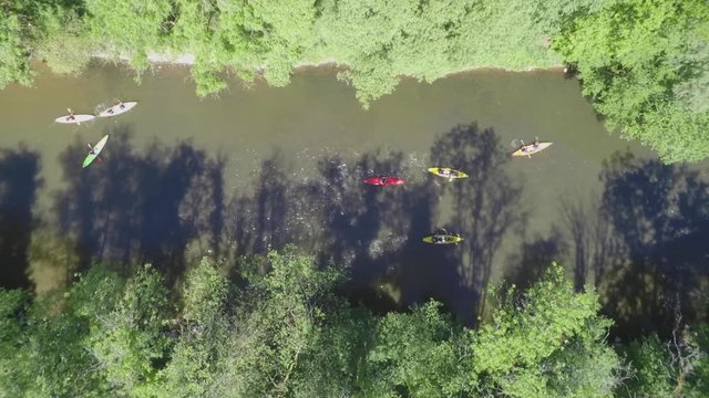 AERIAL: Topshot of kayaks floating down a river on a sunny day.
