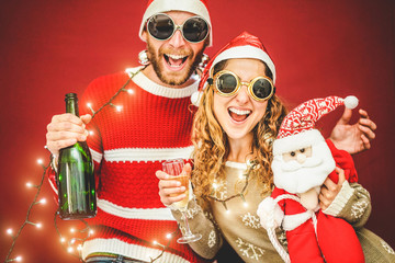 Crazy happy couple celebrating christmas time drinking champagne wearing vintage lights - obrazy, fototapety, plakaty