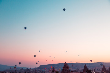 Many huge balloons are flying in the air at the sunrise. Beautiful morning view in Cappadocia, Turkey. Entertainment and new experience for tourists.