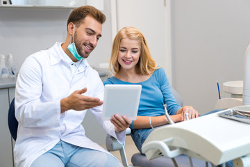 happy young dentist showing tablet to female client