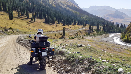 A gravel road to the moutains with bikes under blue sky.