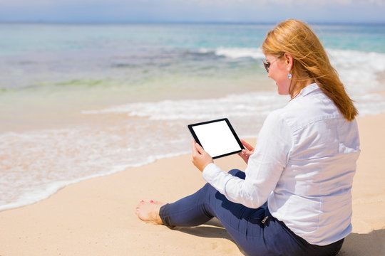 Business woman using tablet on the beach