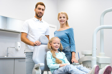 Obraz premium happy young family looking at camera at dentist office