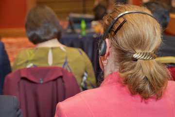Unrecognizable business people using headphones for translation during event . bald security guard...