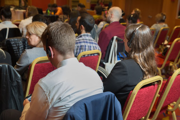 Unrecognizable business people using headphones for translation during event . bald security guard...