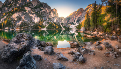 Stones on the coast of Braies lake at sunrise in autumn in Dolomites, Italy. Landscape with...